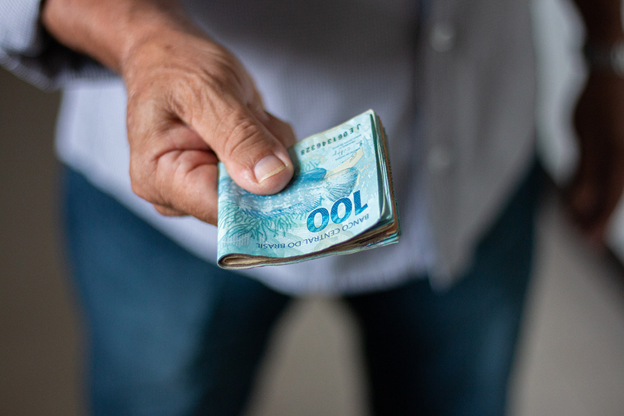 Man holding Brazilian money banknotes by hand.