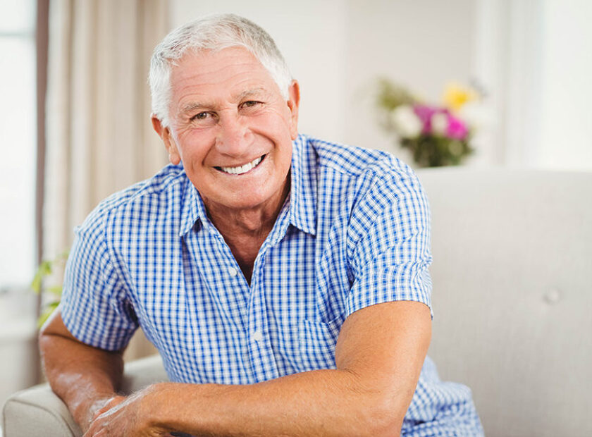 Senior man looking at camera and smiling in living room