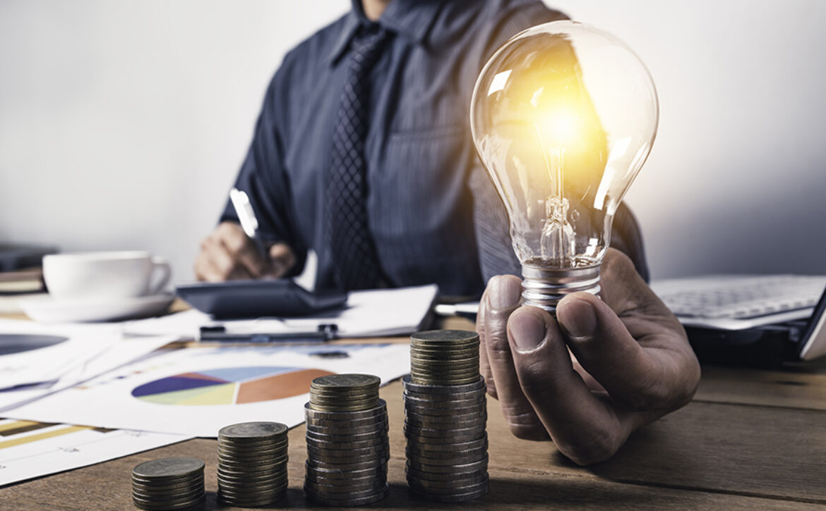 Business man holding a light bulb with coins money and copy spac