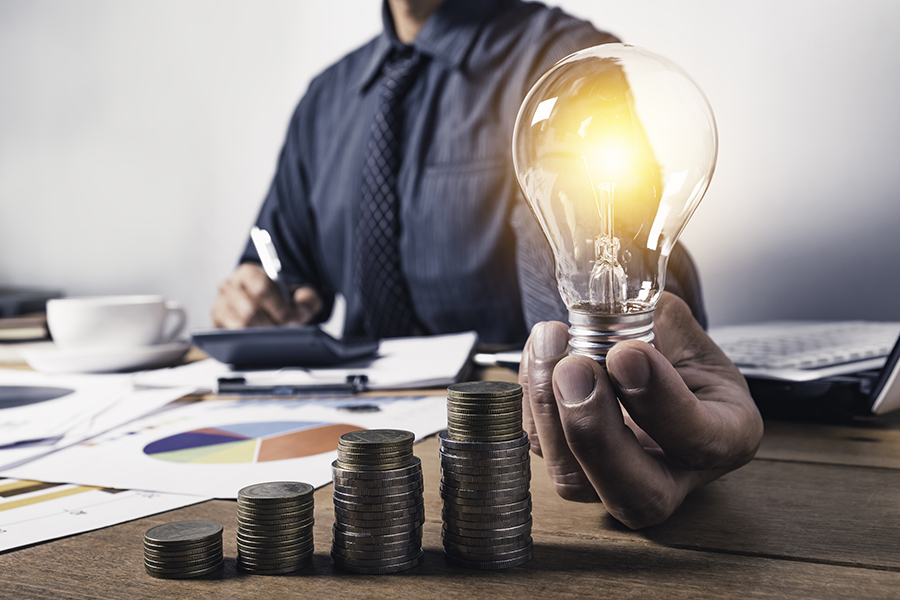 Business man holding a light bulb with coins money and copy spac
