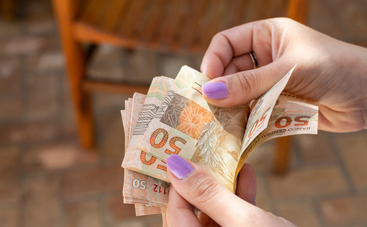woman hand providing Brazilian money banknotes
