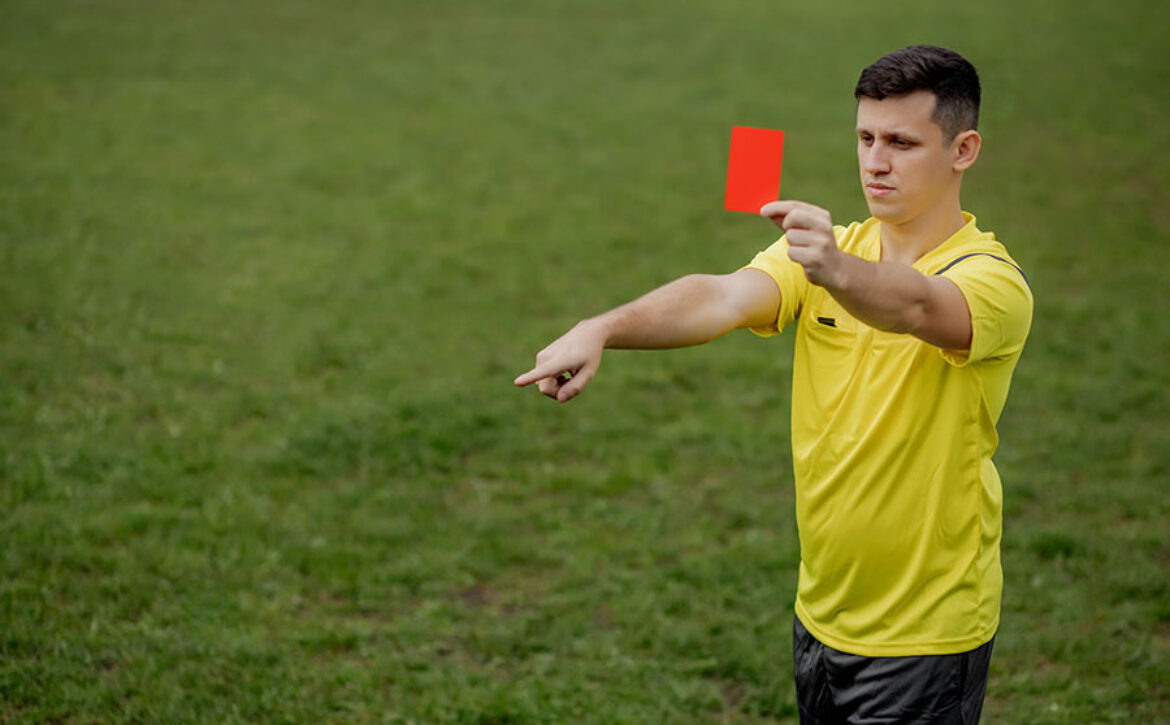 Angry football referee showing a red card and pointing with his hand on penalty