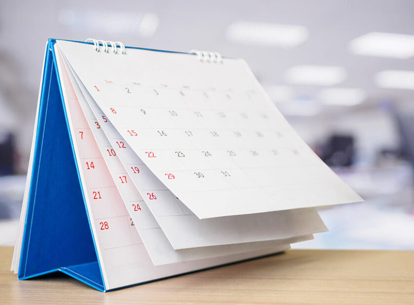 Calendar page flipping sheet on table with blurred office interi